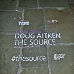 White and purple temporary eco-paint advertising stencil on stone paving for Tate Gallery and Sky Arts at Liverpool Albert Dock.