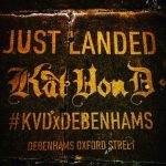 A clean graffiti pavement stencil on dark, textured stone. The advertisement reads "JUST LANDED" at the top, followed by the "Kat Von D" logo in a stylized gothic font. Below that is the hashtag "#KVDxDEBENHAMS" and the location "DEBENHAMS OXFORD STREET".