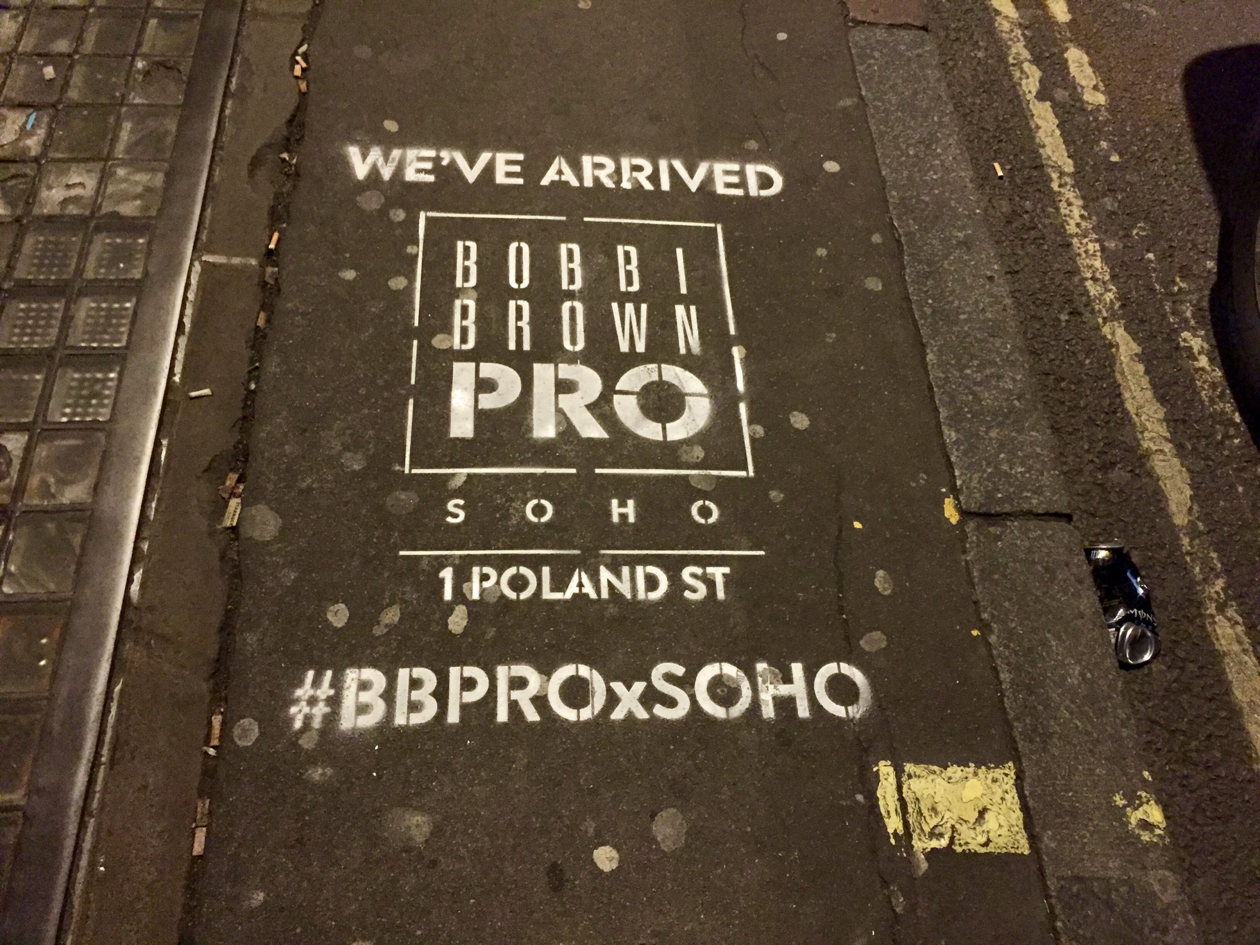 Bright pink and white eco-chalk street advertising stencils sprayed onto a London pavement, promoting a high-impact urban campaign.