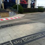 Black water-based temporary paint stencil on a paved walkway at Sky HQ, featuring the Sky Sports F1 HD logo for an internal campus advertising campaign.